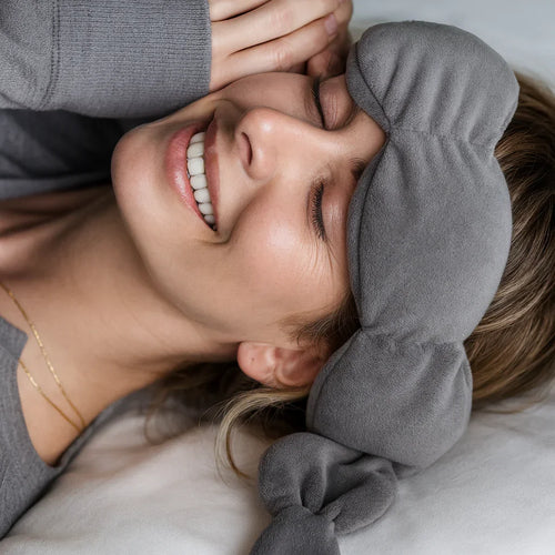 Femme souriante en détente avec un masque de sommeil gris moelleux et un pull gris